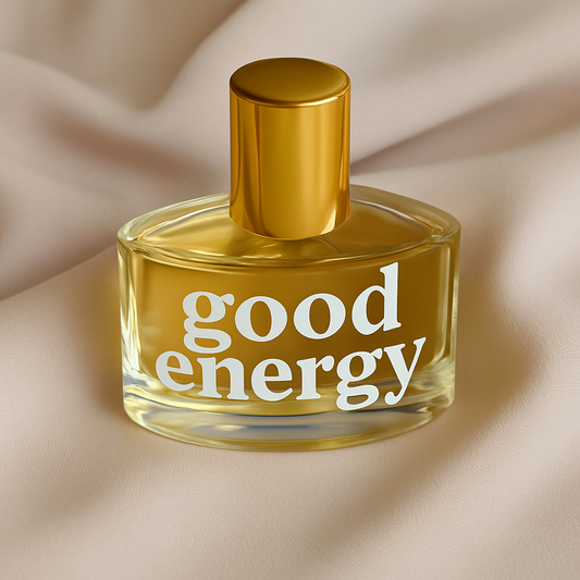 Perfume bottle labeled 'good energy' on a beige fabric background